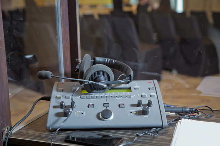 Dolmetschpult mit Headset in einer ISO-4043-Simultankabine – Arbeitsplatz für Konferenzdolmetscher:innen